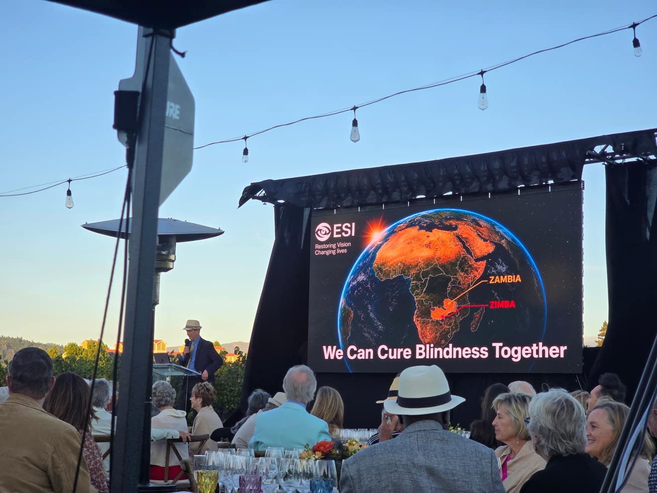 Video wall showing the evening's program, guests seated at dinner