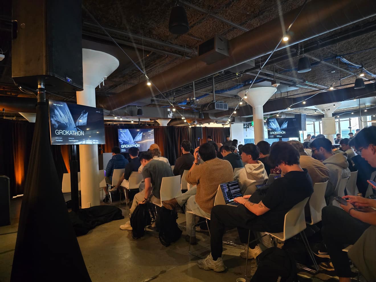 Hackathon attendees working at laptops under the video wall