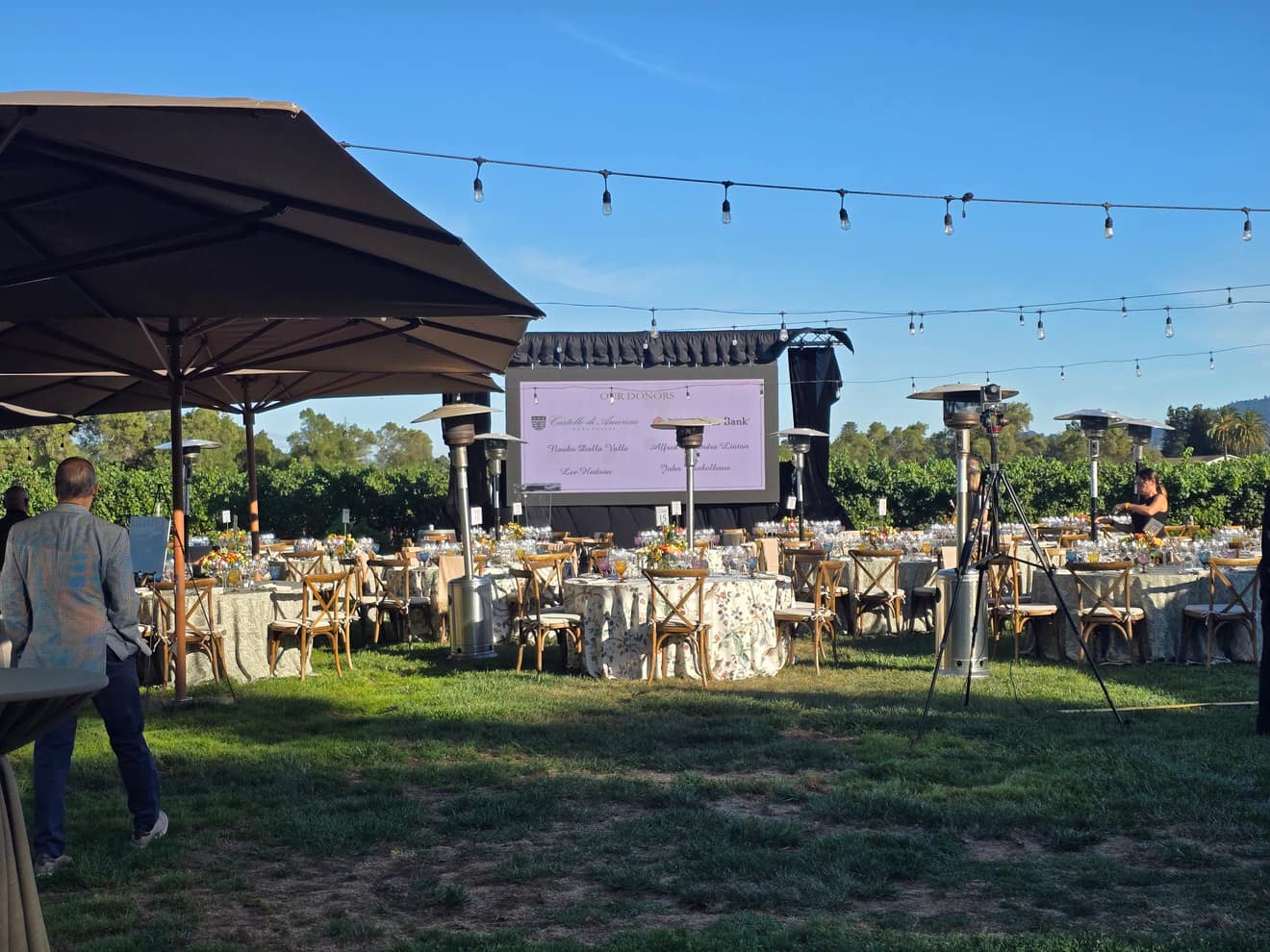 Wide view of the dinner tent, tables set under string lights