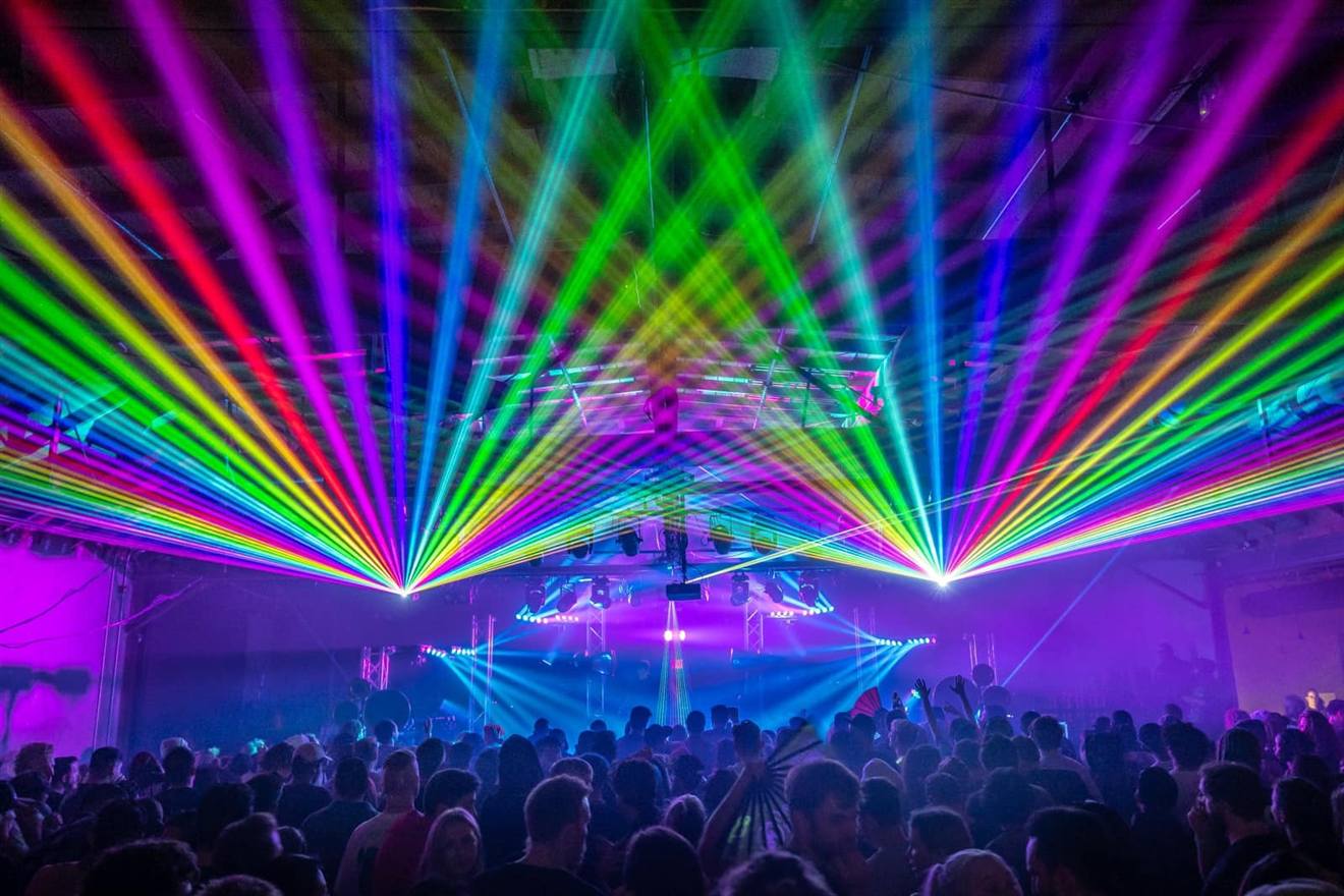 Multicolour laser fan spreading over an indoor crowd