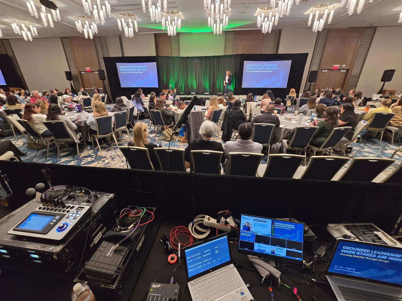 Session in progress, front-of-house console in the foreground, screens showing the program